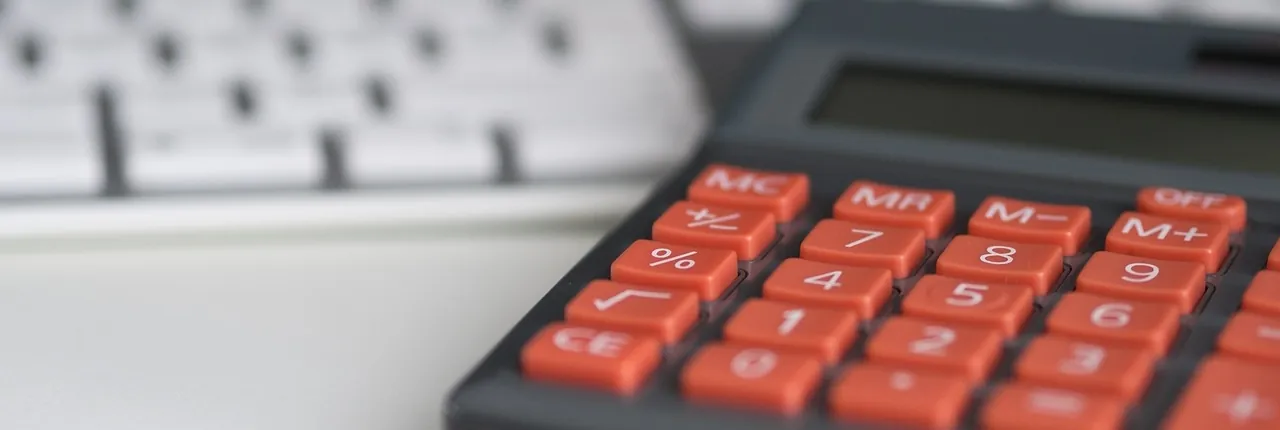 Calculatrice aux touches orange devant un clavier d’ordinateur