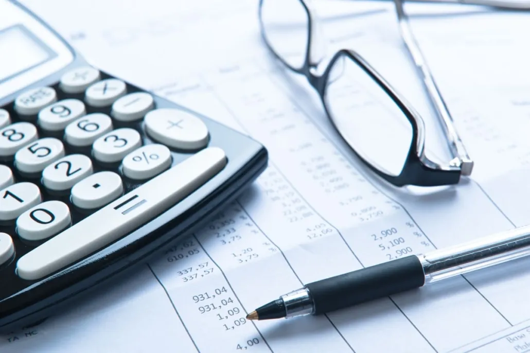 Calculatrice, lunettes et stylo posés sur des documents comptables